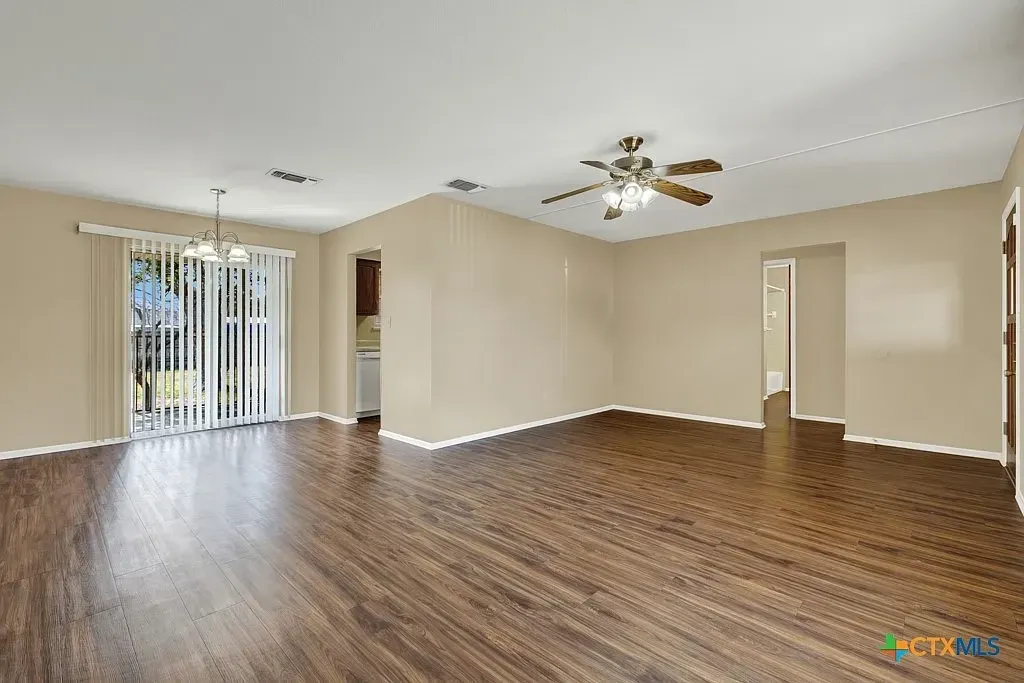 The living and dining area of the Gruene Road Residence, with wood-look flooring and a sliding door to the backyard.
